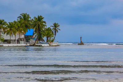 Palm-lined Isla Grande beach with the offshore Cristo del Mar statue on Panama's Caribbean coast
