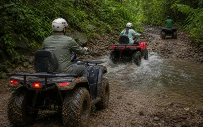 ATV riders crossing a rocky Cerro Azul river on the trail