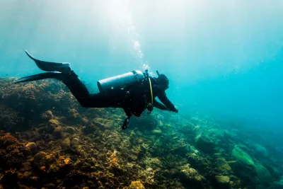 Diver in a full wetsuit exploring the coral reef at Playa Huerta near Portobelo