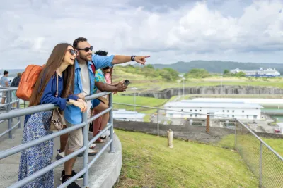 Tourists looking out over Panama Canal locks from a visitor center overlook