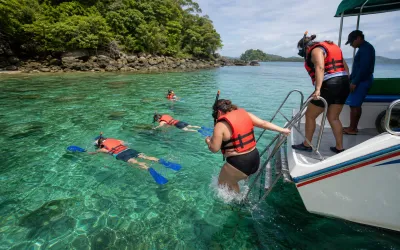 Snorkelers entering clear Caribbean water near Isla Grande