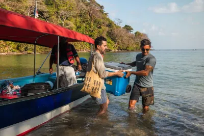 Travelers stepping off a covered tour boat onto a Caribbean beach near Portobelo